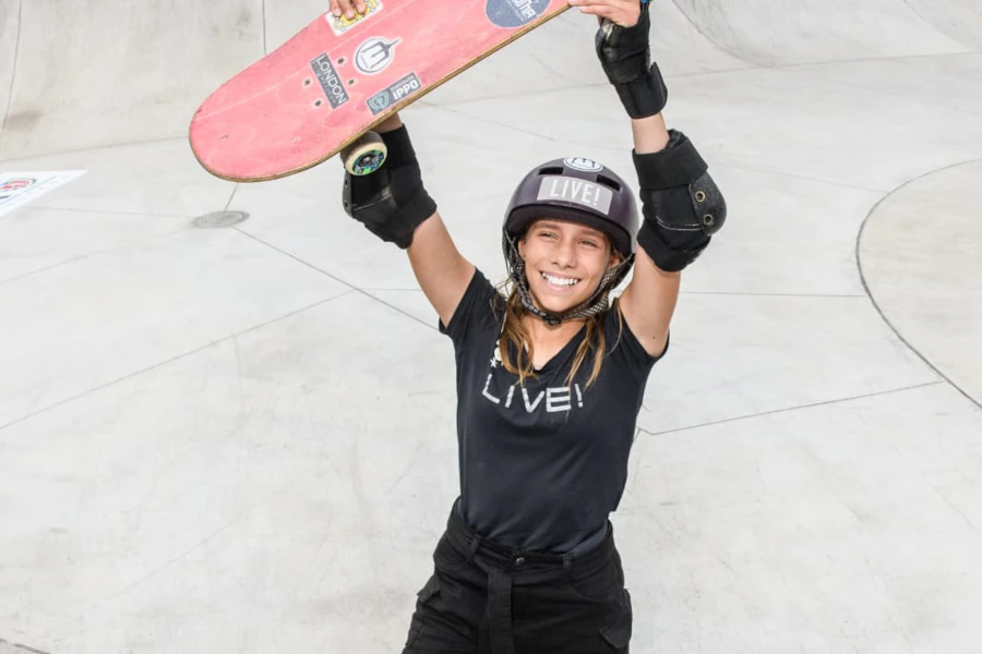 Ana Aguiar sorrindo e levantando o skate acima da cabeça