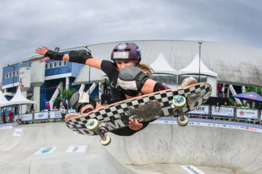Manobra de "grab" sobre uma elevação central em uma pista de skate profissional.